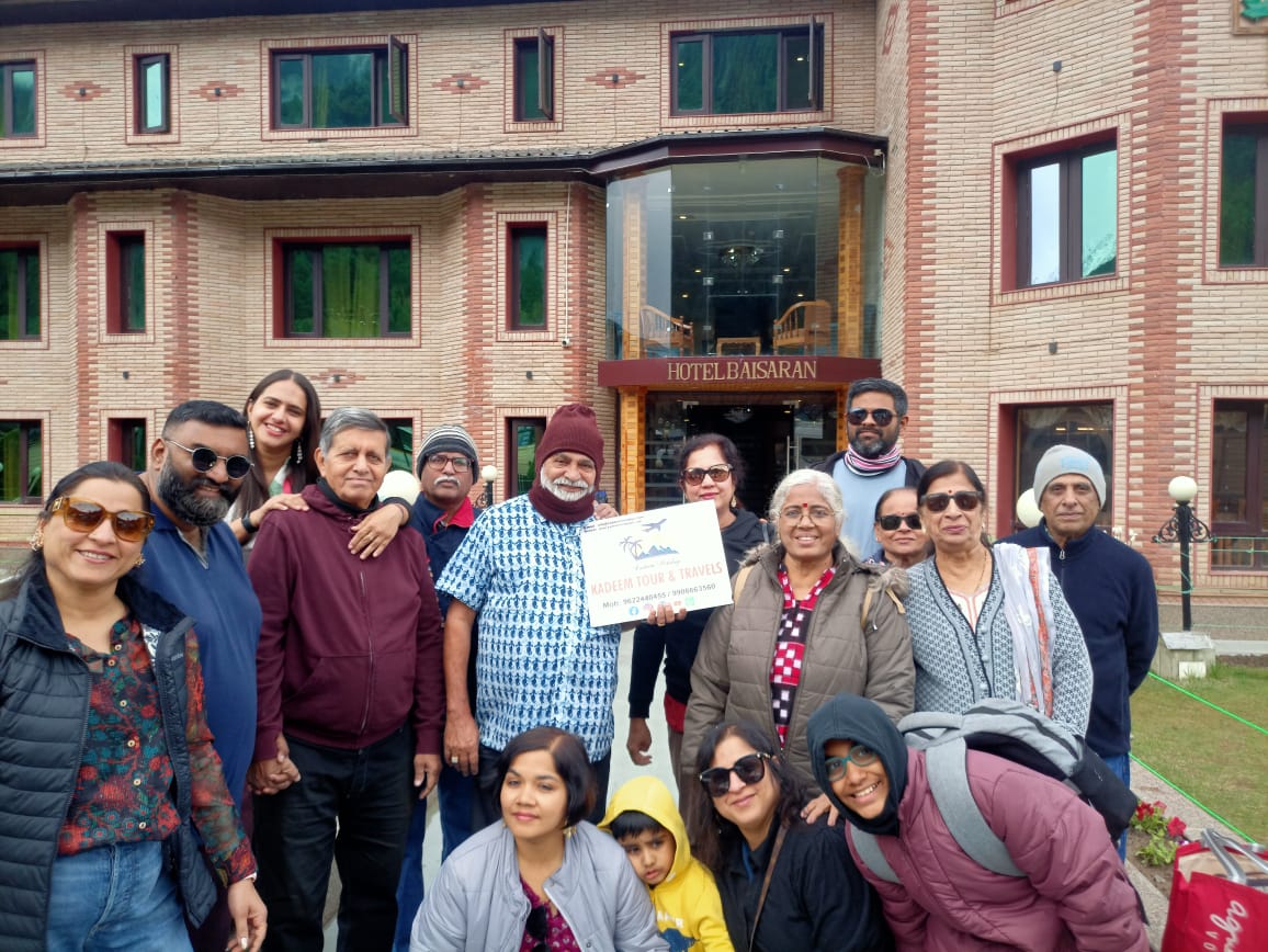 kashmir group tour package,group of people hold kadeem holidays banner