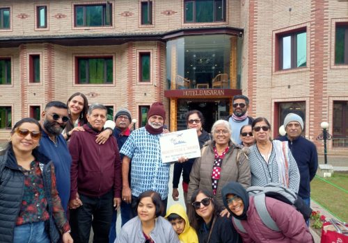 kashmir group tour package,group of people hold kadeem holidays banner
